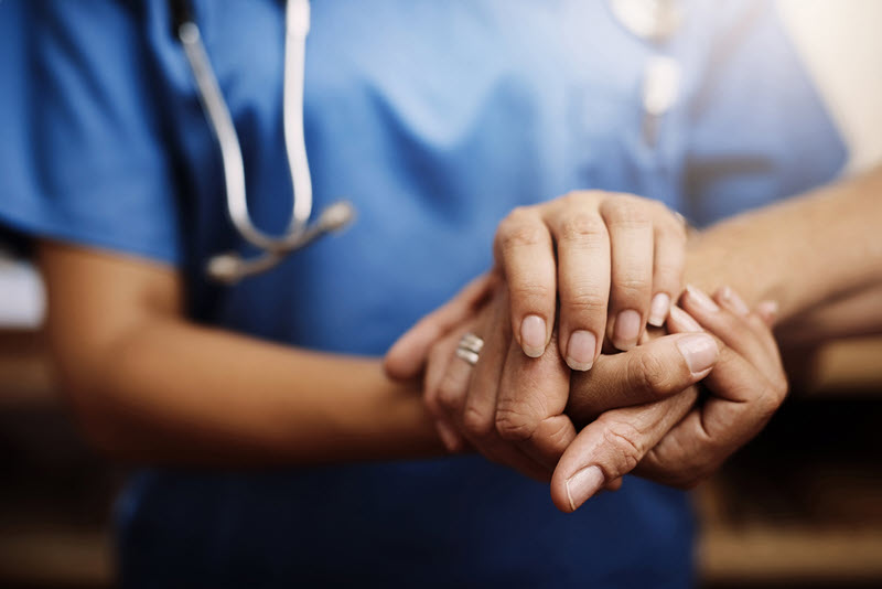 Patient and healthcare professional hold hands